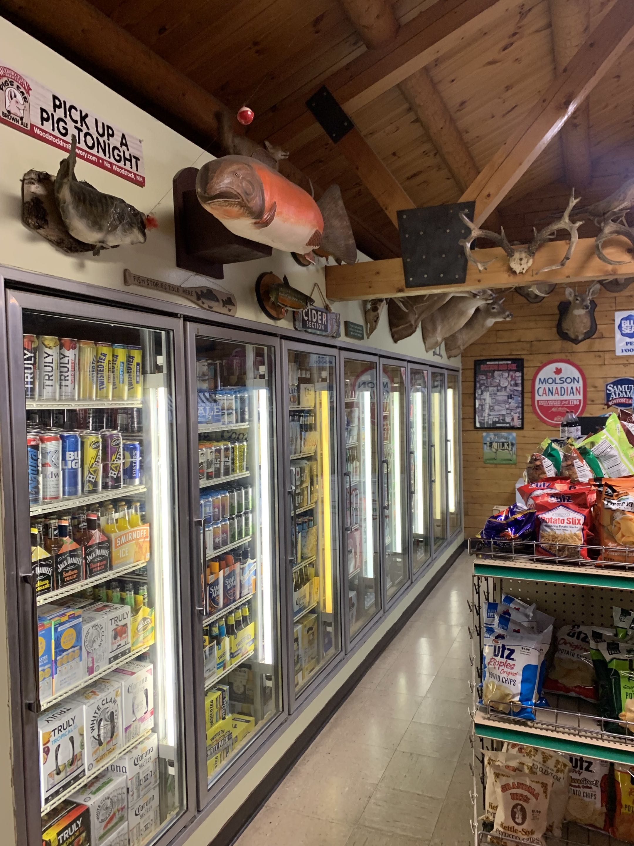 Craft beer cooler wall with fish mounts and Pick Up a Pig Tonight sign
